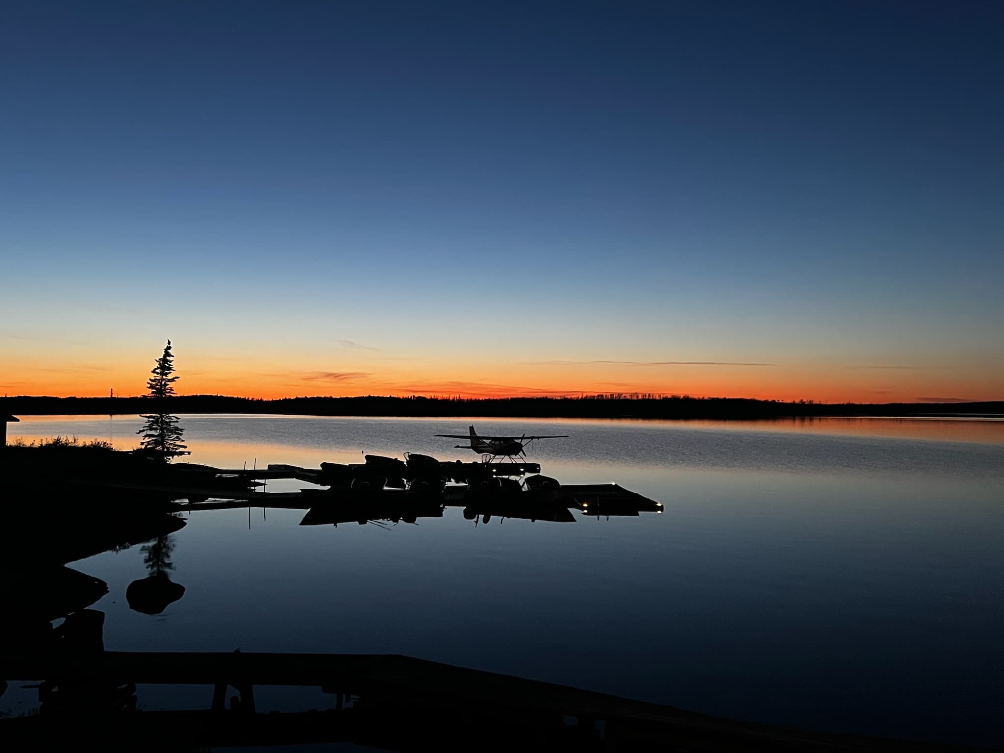 Dogskin Lake Lodge dock and floatplane silhouetted against a Manitoba sunset